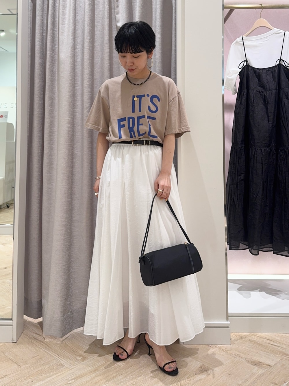 ベージュ系のTシャツ/カットソー、ホワイト系のスカート、ブラック系のショルダーバッグを着用したレディースの春コーディネートの1枚目の写真