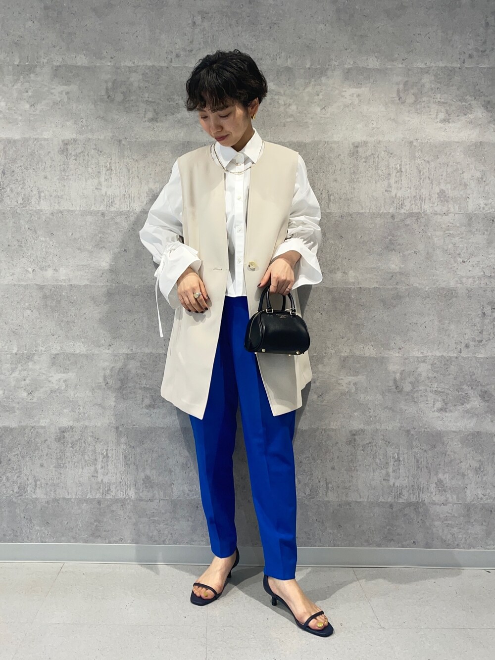 ブルー系のその他パンツ、ブラック系のボストンバッグ、ホワイト系のベストを着用したレディースの春コーディネートの1枚目の写真