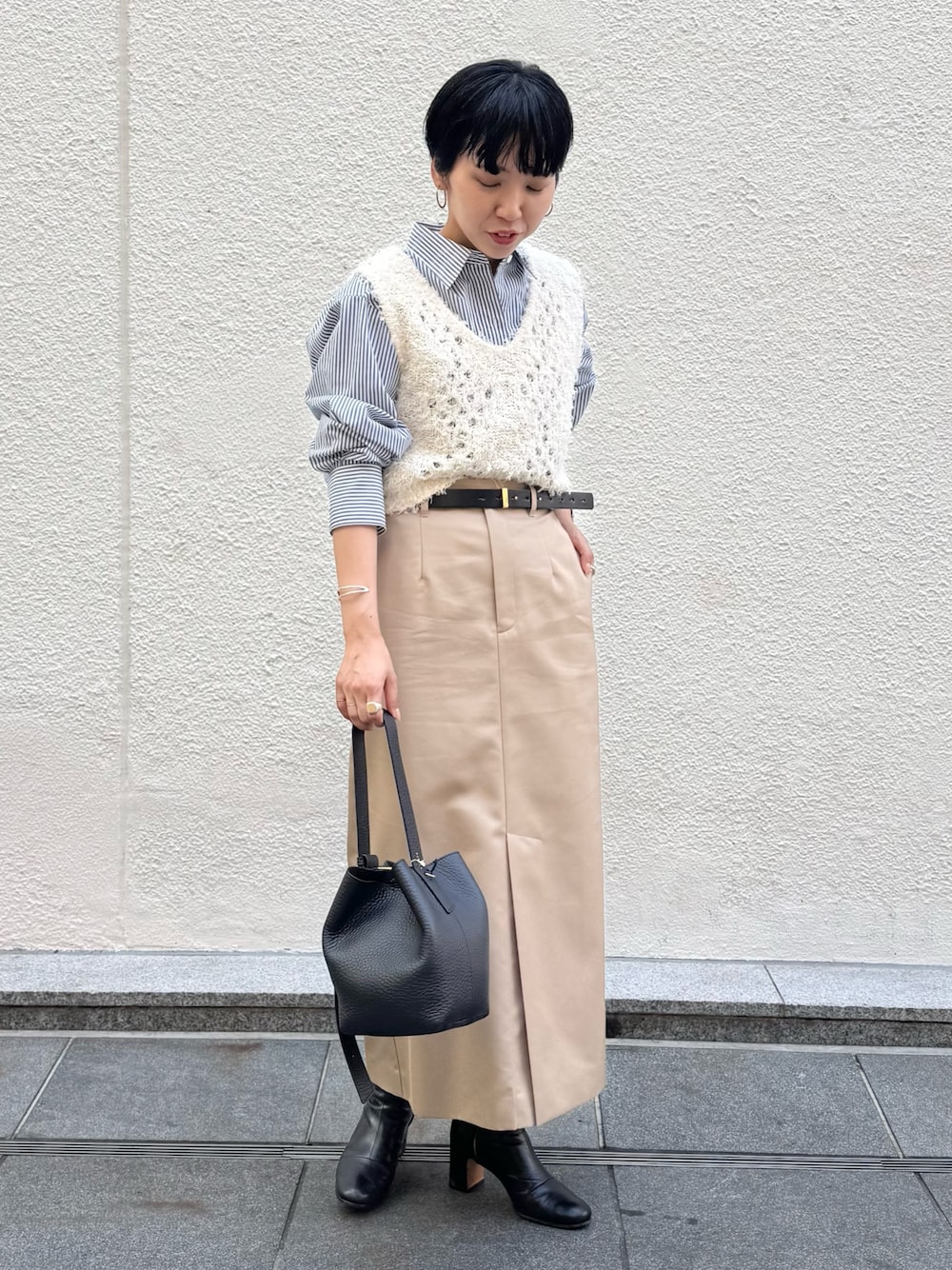 ブルー系のシャツ/ブラウス、ホワイト系のベスト、ベージュ系のスカートを着用したレディースの秋コーディネートの1枚目の写真