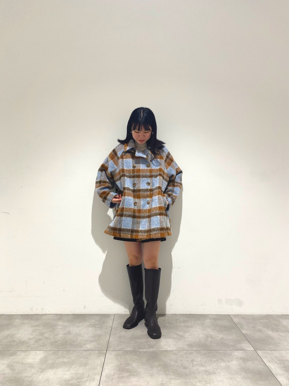 ブラウン系のブーツ、ブルー系のステンカラーコート、ブラウン系のスラックスを着用したレディースの冬コーディネートの1枚目の写真