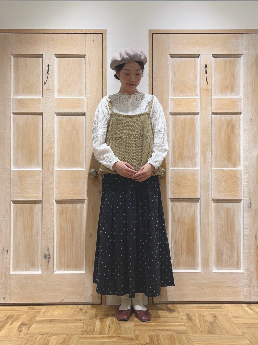 イエロー系のニット/セーター、ホワイト系のシャツ/ブラウス、ブラック系のスカートを着用したレディースの秋コーディネートの1枚目の写真