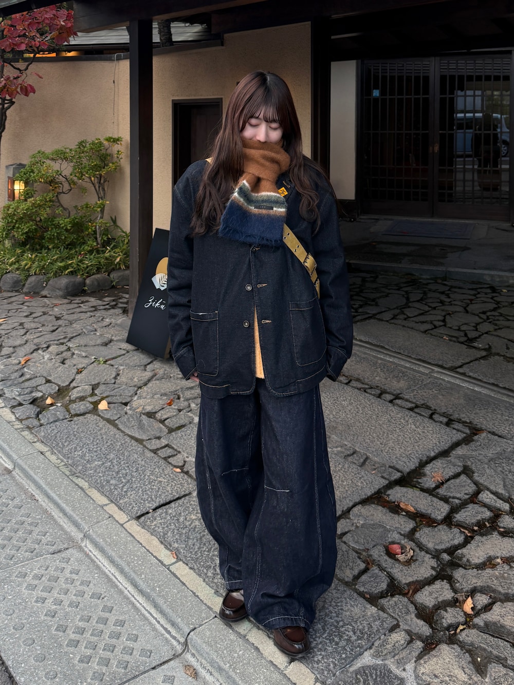 イエロー系のショルダーバッグ、ブルー系のデニムジャケット、ブルー系のデニムパンツを着用したレディースの秋コーディネートの1枚目の写真