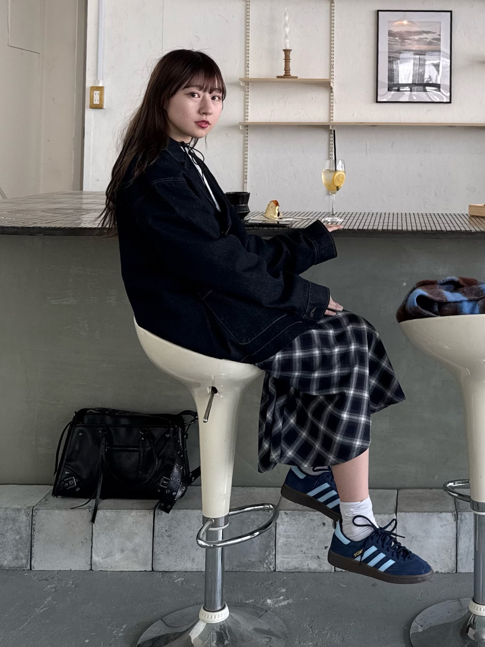 ブルー系のデニムジャケット、ブルー系のスカート、ブルー系のスニーカーを着用したレディースの冬コーディネートの1枚目の写真