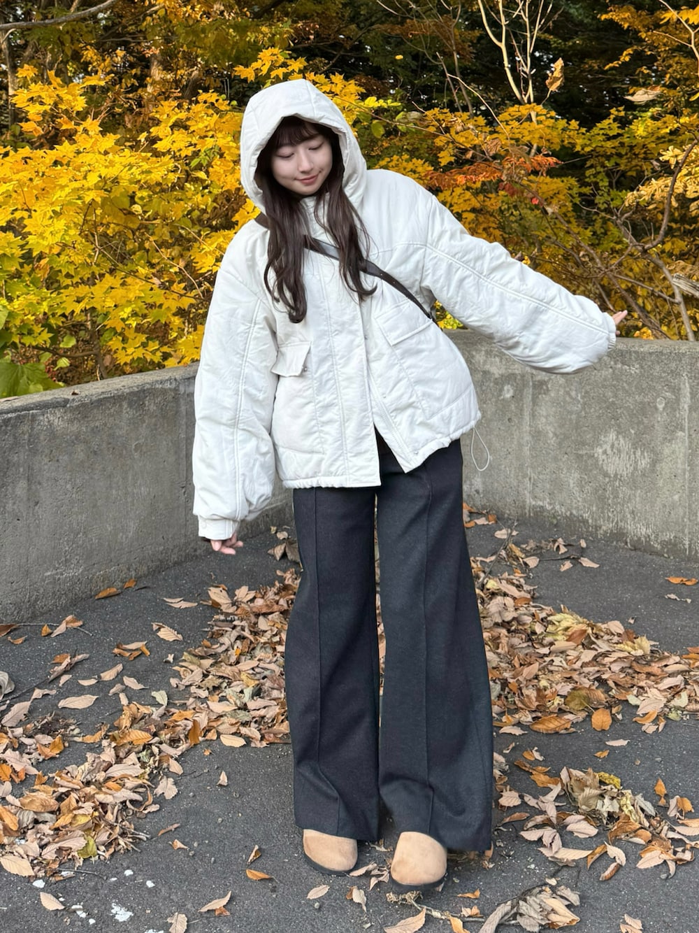 ホワイト系のブルゾン、ブラウン系のサンダル、グレー系のスラックスを着用したレディースの秋コーディネートの1枚目の写真