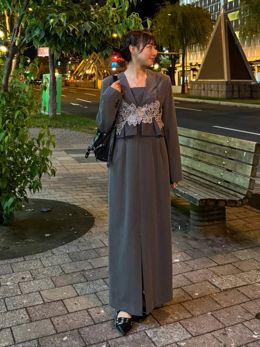 グレー系のドレス、ブラック系のパンプス、ブラック系のショルダーバッグを着用したレディースの秋コーディネートの1枚目の写真