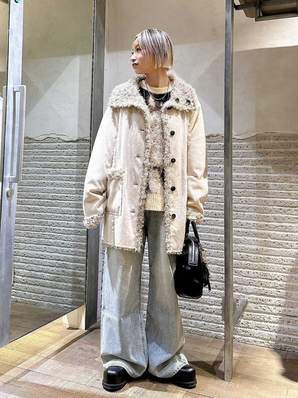 ブラウン系のニット/セーター、ブルー系のデニムパンツ、ブラック系のボストンバッグを着用したレディースの冬コーディネートの1枚目の写真