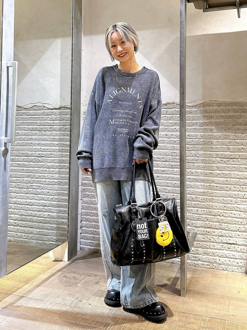 ブラック系のサンダル、ブルー系のデニムパンツ、ブラック系のトートバッグを着用したレディースの秋コーディネートの1枚目の写真