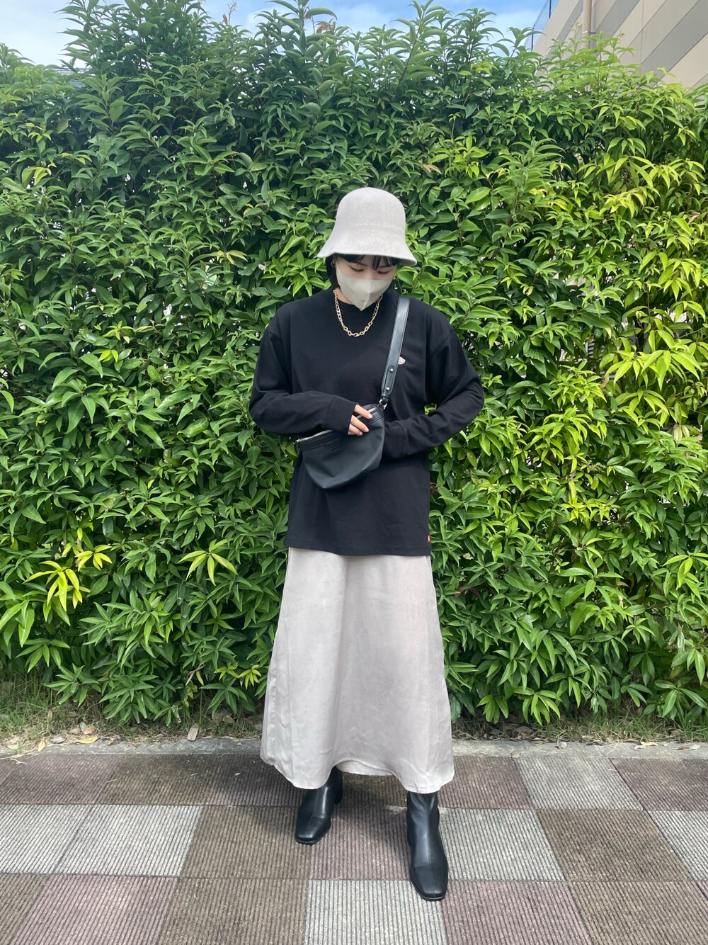 ブラック系のショルダーバッグ、グレー系のスカート、ブラック系のブーツを着用したレディースの秋コーディネートの1枚目の写真