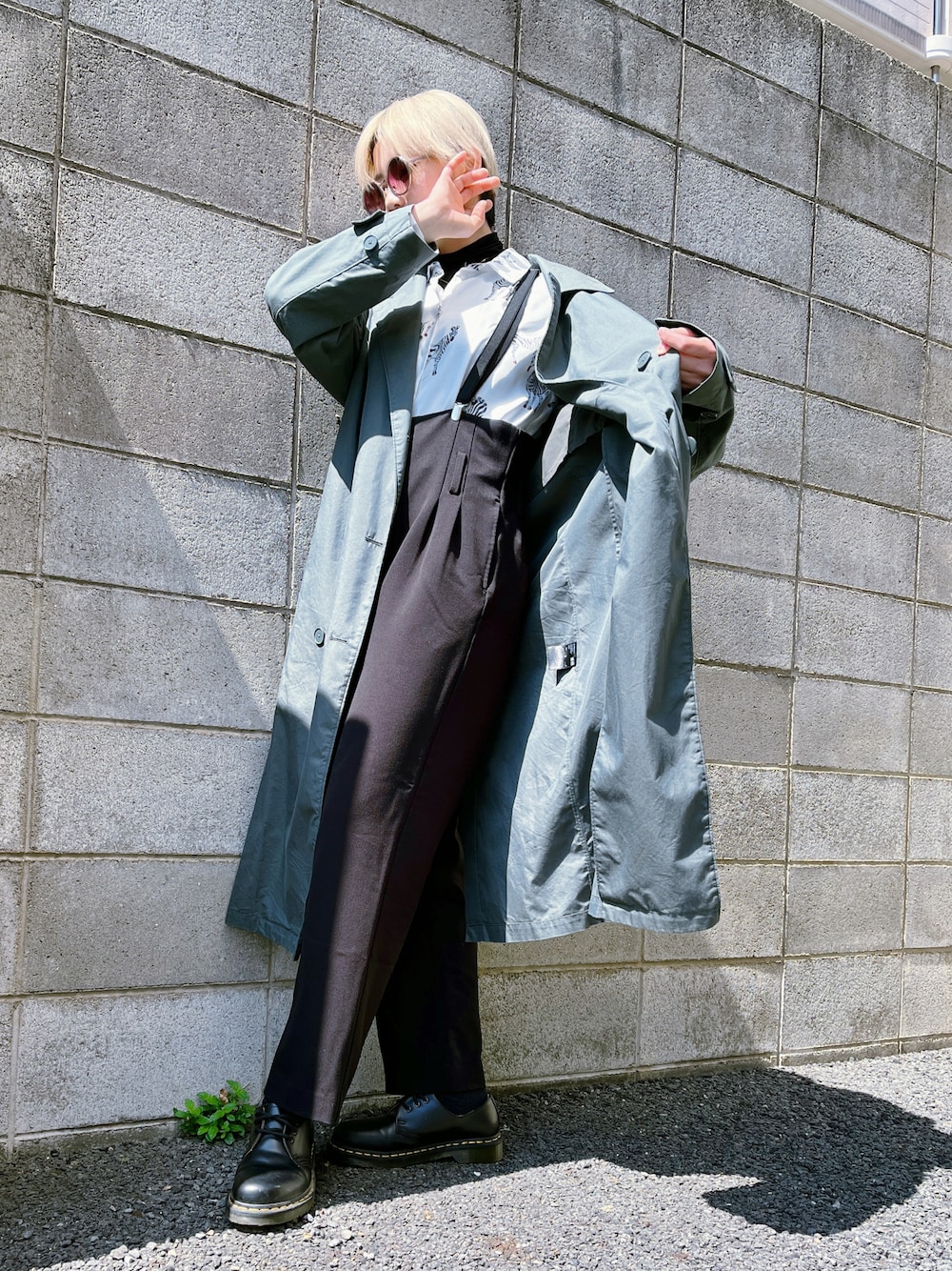 グリーン系のトレンチコート、ホワイト系のシャツ/ブラウス、ブラック系のサロペット/オーバーオールを着用したレディースの春コーディネートの1枚目の写真