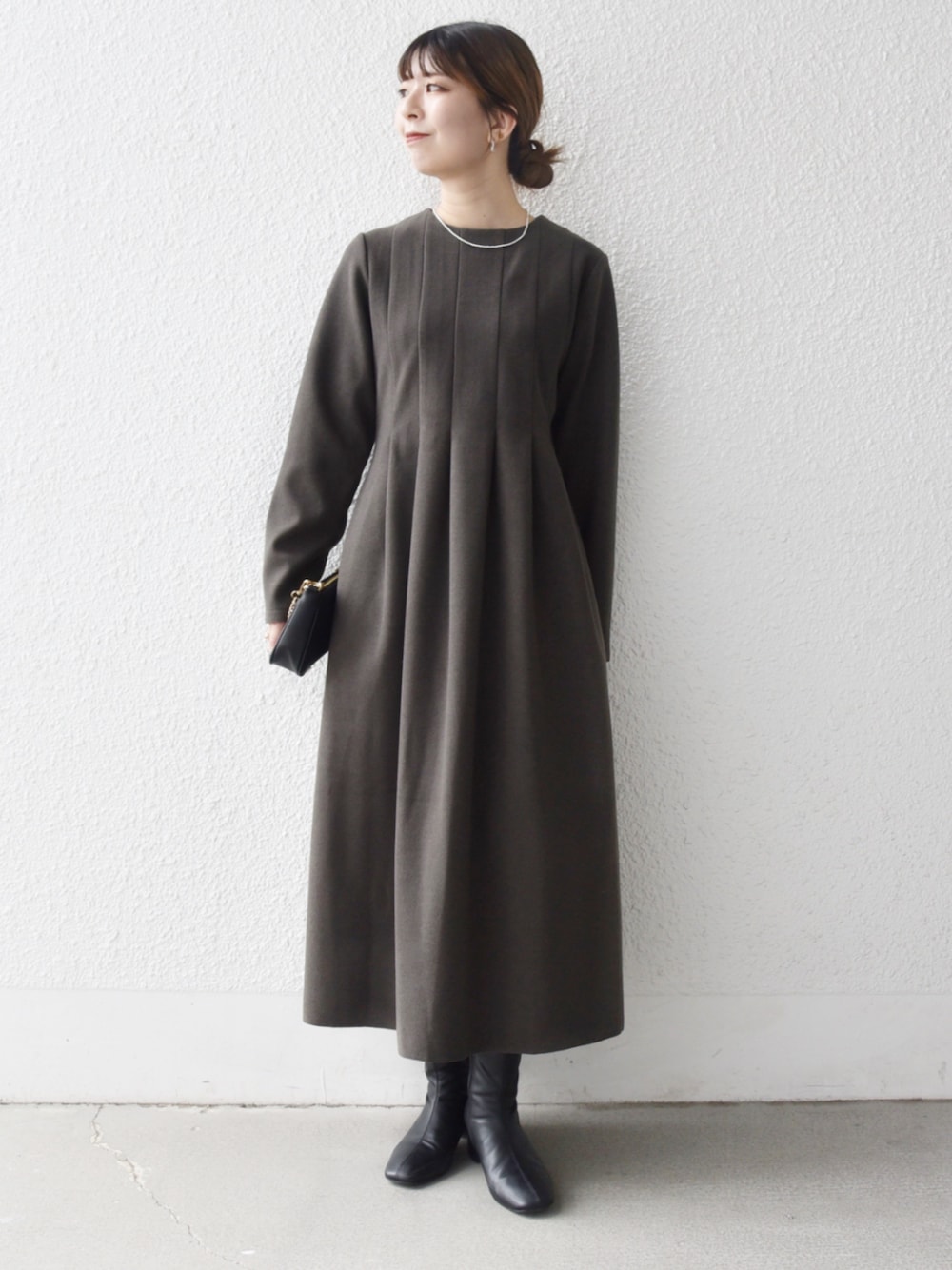 グリーン系のワンピースを着用したレディースの秋コーディネートの1枚目の写真