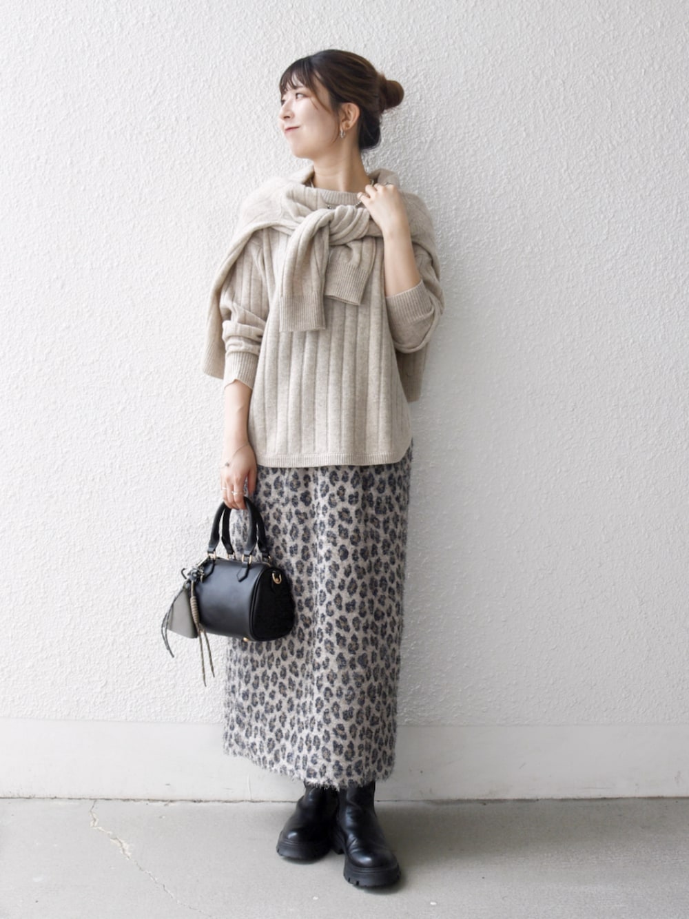 ブラック系のボストンバッグ、ベージュ系のカーディガン/ボレロ、ベージュ系のスカートを着用したレディースの秋コーディネートの1枚目の写真