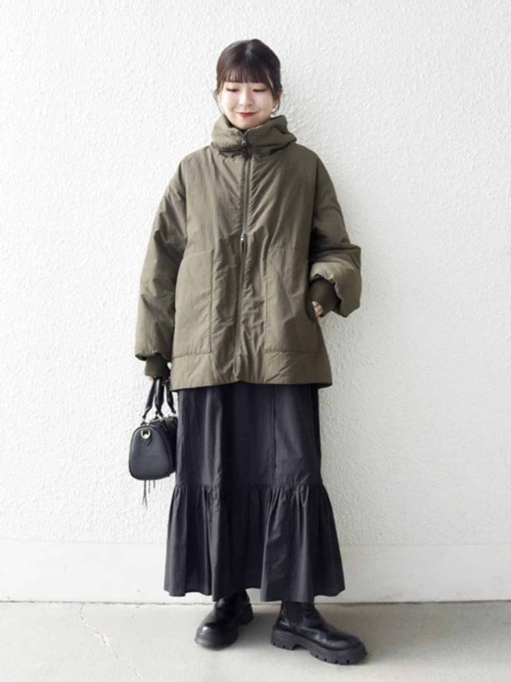 ブラック系のブーツ、ブラック系のボストンバッグ、グリーン系のブルゾンを着用したレディースの冬コーディネートの1枚目の写真