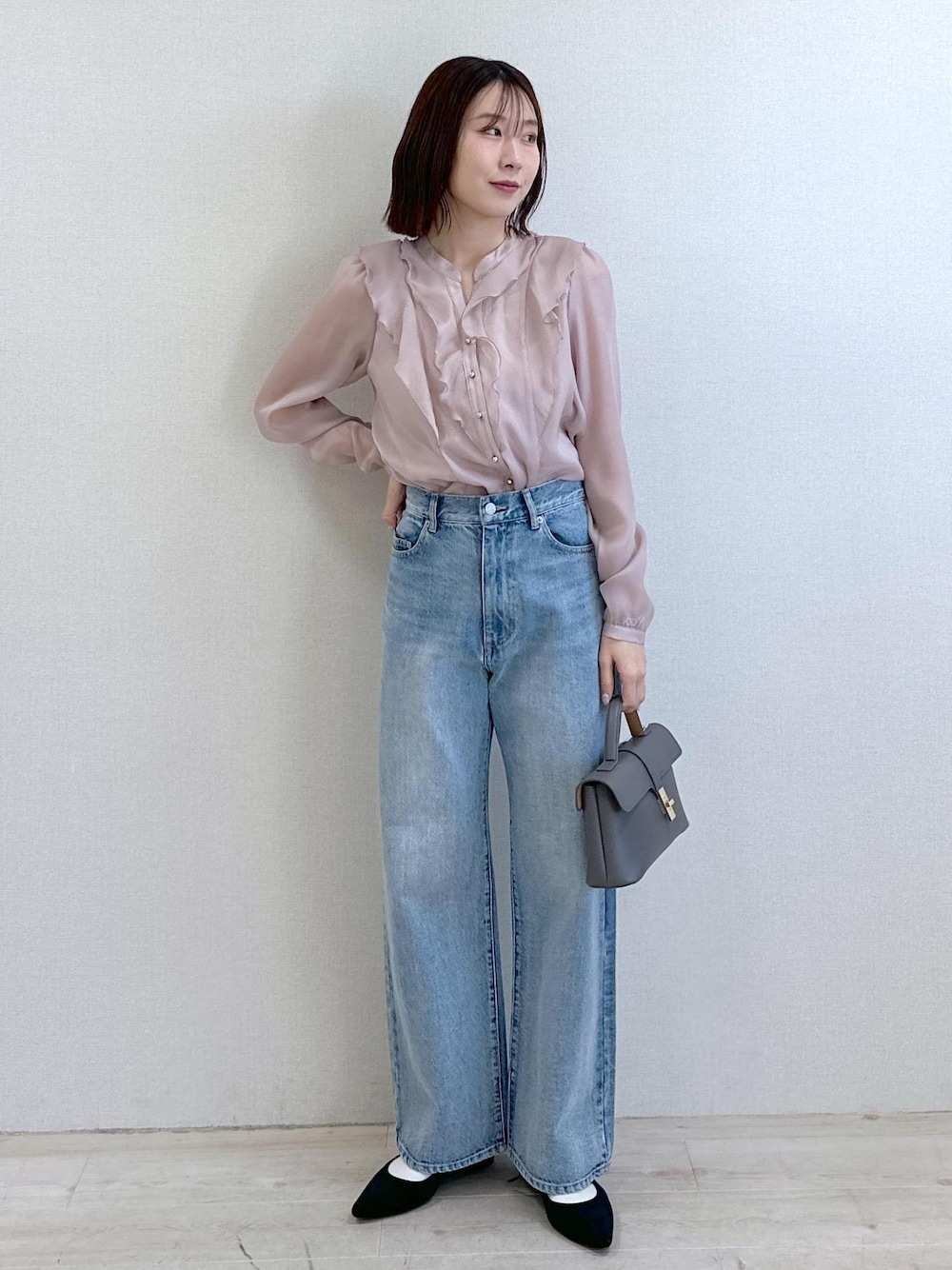 ブルー系のデニムパンツ、ブラック系のパンプス、グレー系のショルダーバッグを着用したレディースの春コーディネートの1枚目の写真