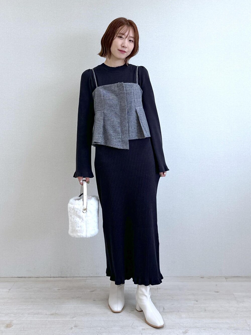 ホワイト系のショルダーバッグ、ホワイト系のブーツ、ブラック系のワンピースを着用したレディースの秋コーディネートの1枚目の写真