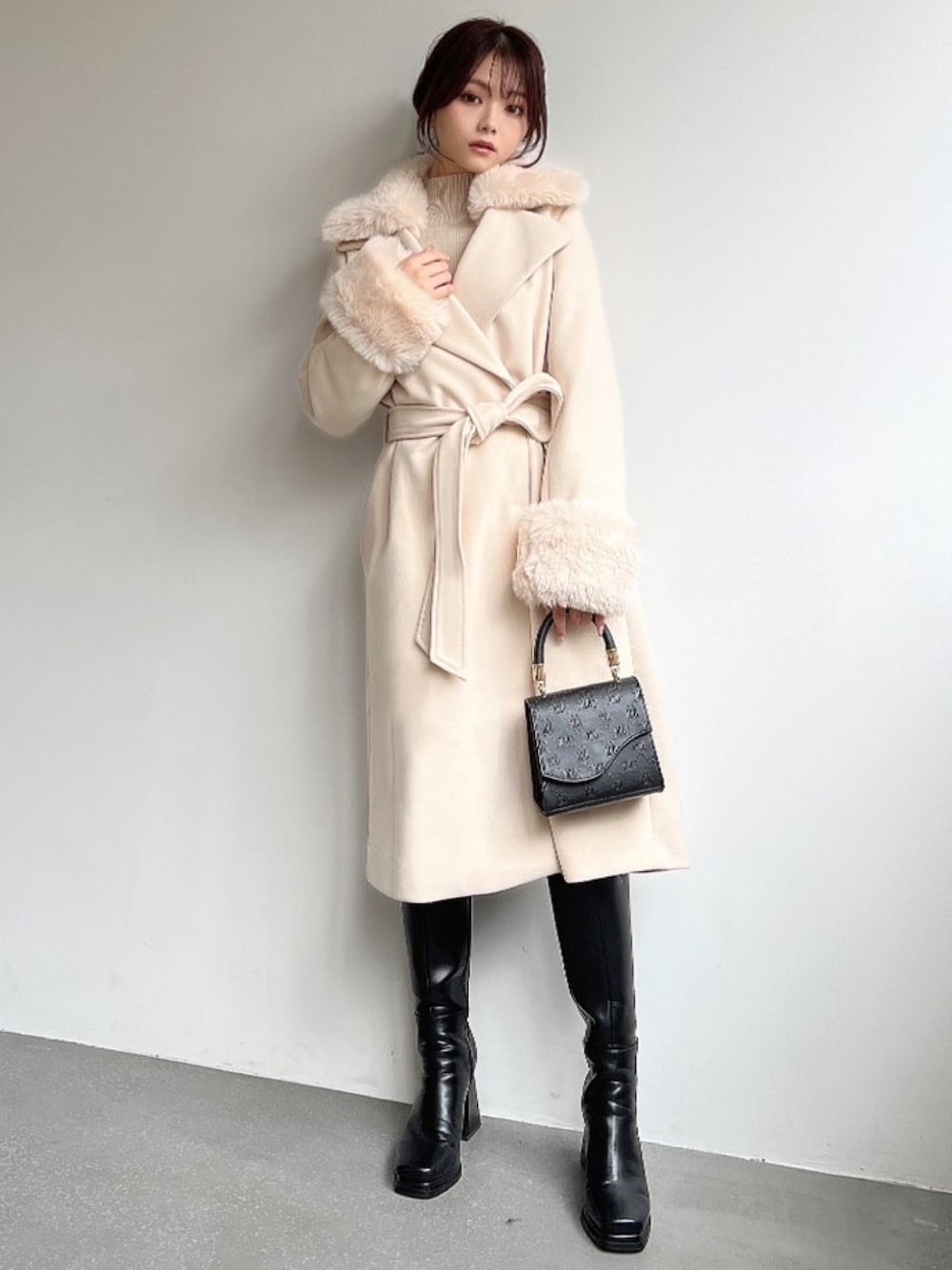 ホワイト系のその他アウター、ベージュ系のニット/セーター、ブラック系のハンドバッグを着用したレディースの冬コーディネートの1枚目の写真