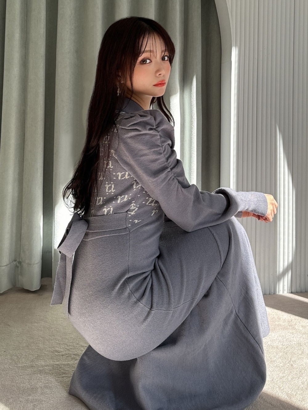 ブルー系のワンピース、ブラック系のハンドバッグ、ブラック系のパンプスを着用したレディースの冬コーディネートの1枚目の写真