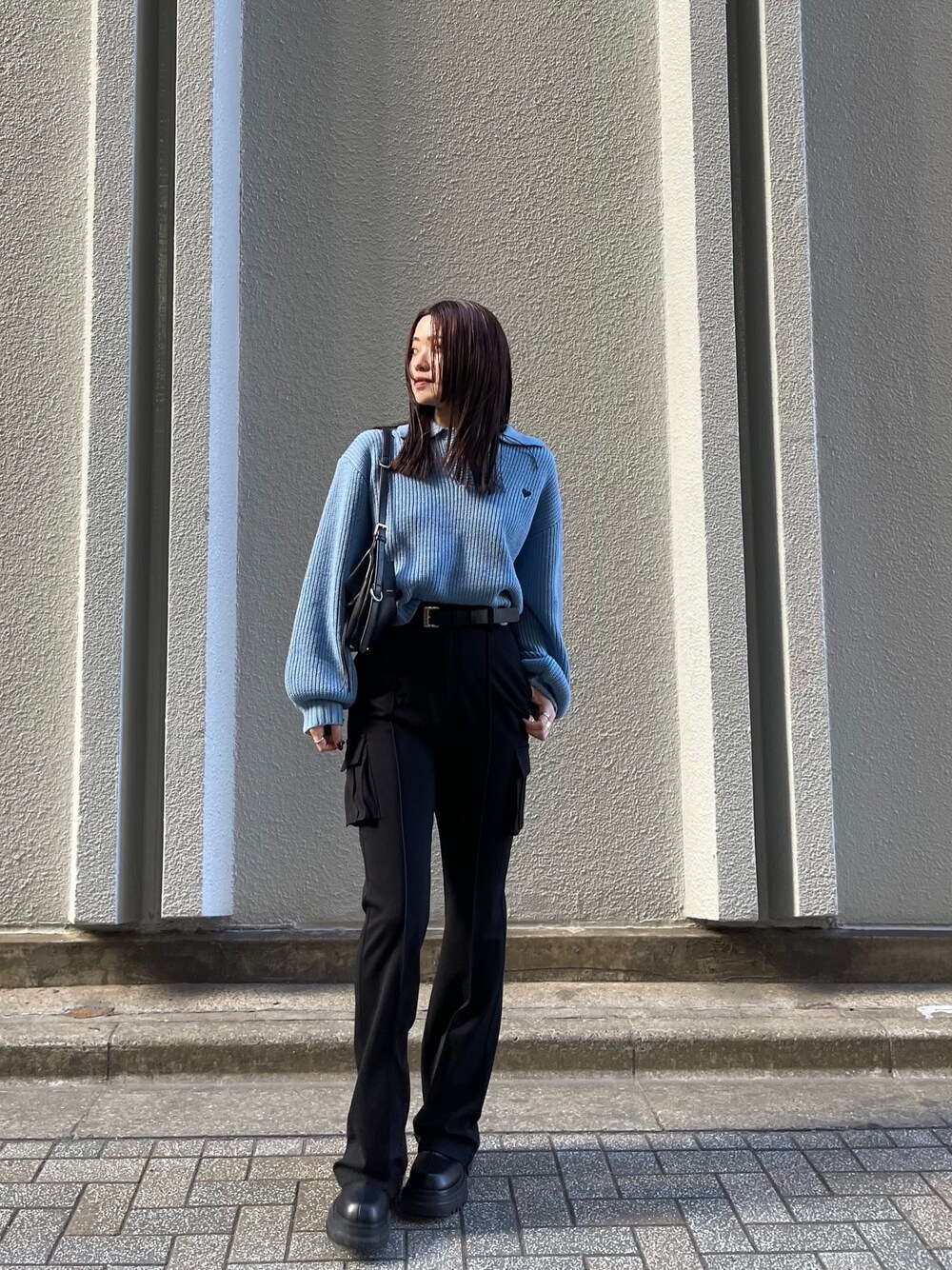 ブルー系のニット/セーター、ブラック系のカーゴパンツ、ブラック系のブーツを着用したレディースの冬コーディネートの1枚目の写真