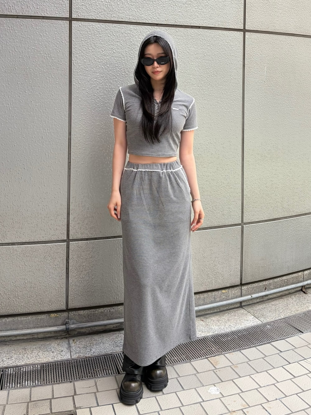 グレー系のスカート、グレー系のTシャツ/カットソー、ブラック系のブーツを着用したレディースの春コーディネートの1枚目の写真