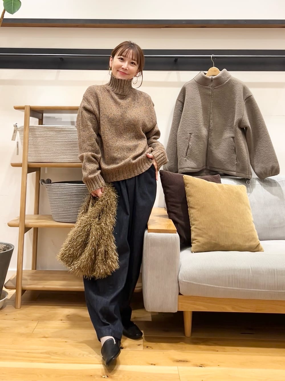 ブラウン系のニット/セーター、ブラウン系のトートバッグ、ブルー系のデニムパンツを着用したレディースの冬コーディネートの1枚目の写真