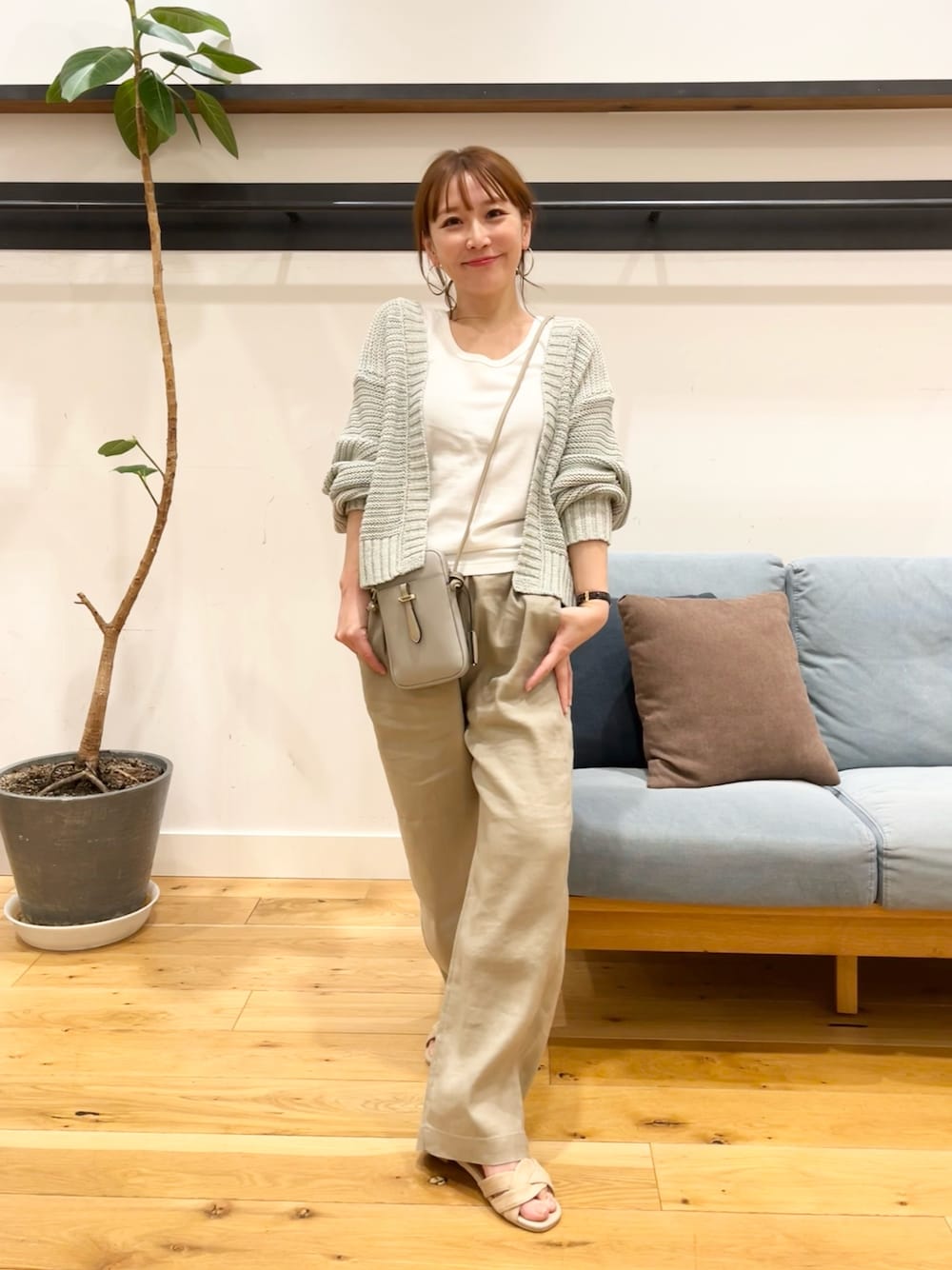 グリーン系のカーディガン/ボレロ、グレー系のショルダーバッグ、ベージュ系のパンツを着用したレディースの春コーディネートの1枚目の写真
