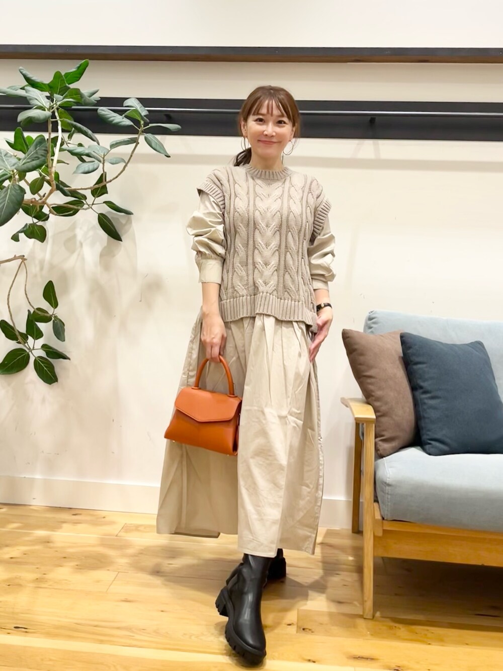 ベージュ系のワンピース、ブラック系のショルダーバッグ、ブラック系のブーツを着用したレディースの秋コーディネートの1枚目の写真