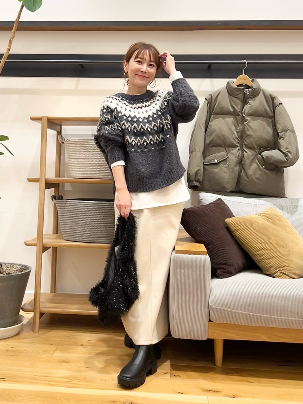 グレー系のニット/セーター、ブラウン系のトートバッグ、ホワイト系のスカートを着用したレディースの冬コーディネートの1枚目の写真