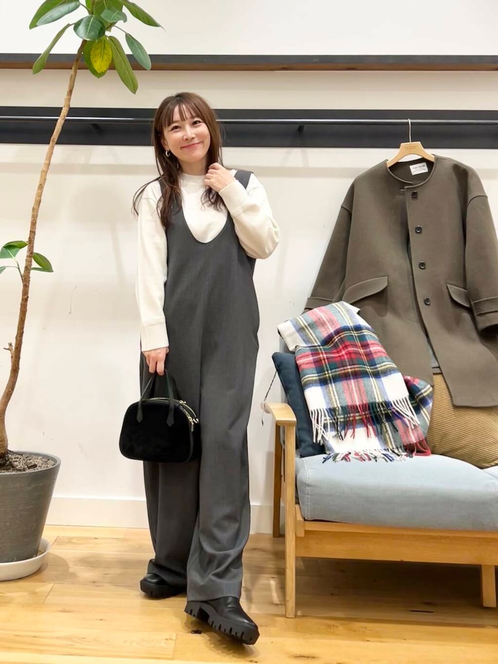 グリーン系のノーカラーコート、ホワイト系のニット/セーター、ブラック系のショルダーバッグを着用したレディースの冬コーディネートの1枚目の写真