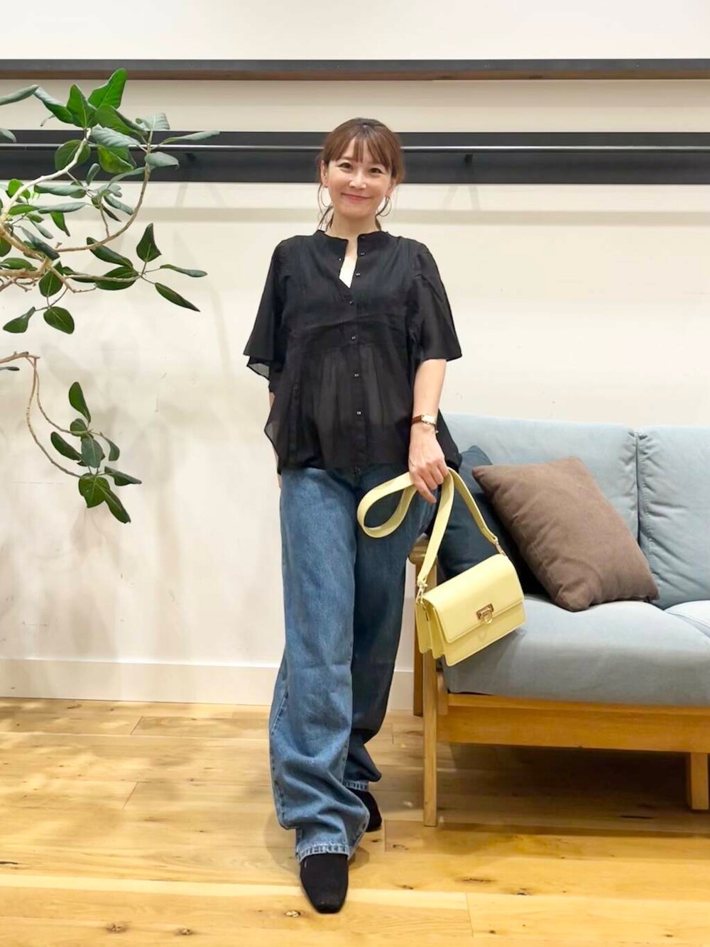 ブルー系のデニムパンツ、ブラック系のシャツ/ブラウス、イエロー系のショルダーバッグを着用したレディースの夏コーディネートの1枚目の写真