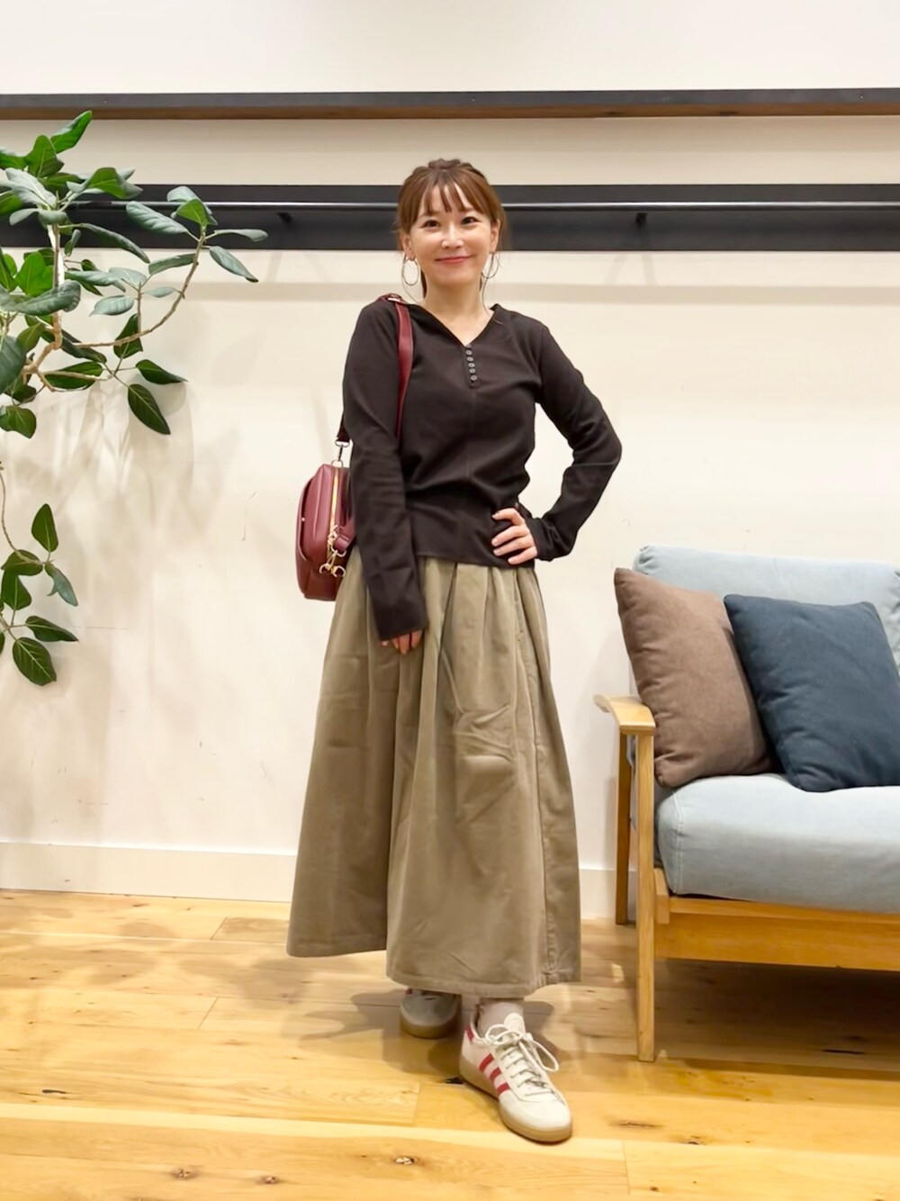 ブラウン系のTシャツ/カットソー、ベージュ系のスカート、グリーン系のショルダーバッグを着用したレディースの秋コーディネートの1枚目の写真