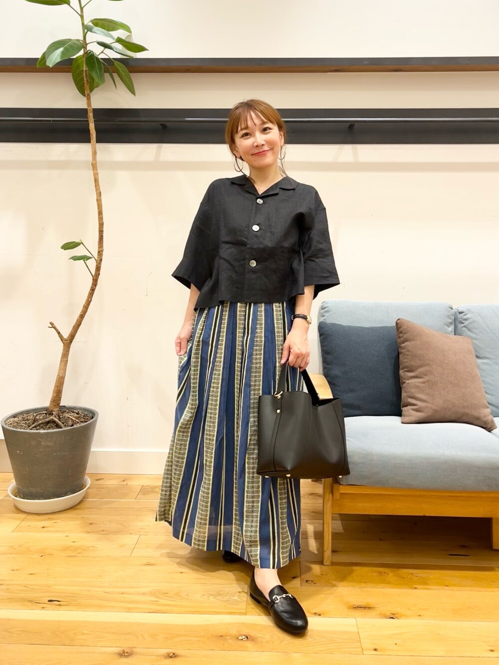 ブラック系のシャツ/ブラウス、グリーン系のスカート、ブラック系のトートバッグを着用したレディースの春コーディネートの1枚目の写真