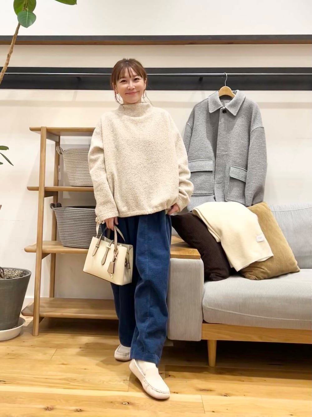 ホワイト系のハンドバッグ、グレー系のその他アウター、ホワイト系のスリッポンを着用したレディースの冬コーディネートの1枚目の写真