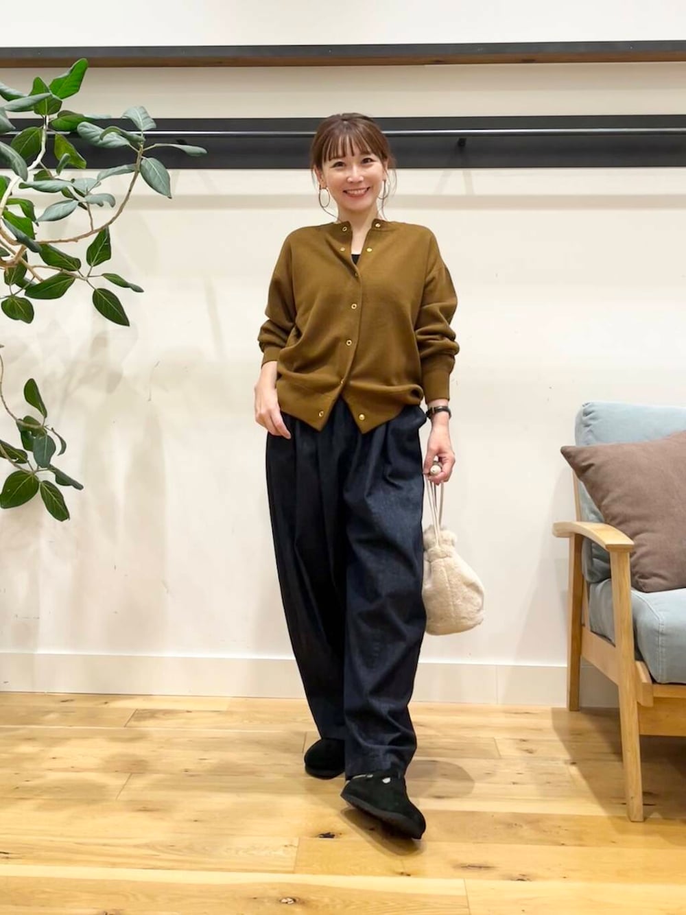 ブルー系のデニムパンツ、イエロー系のカーディガン/ボレロ、ホワイト系のショルダーバッグを着用したレディースの秋コーディネートの1枚目の写真