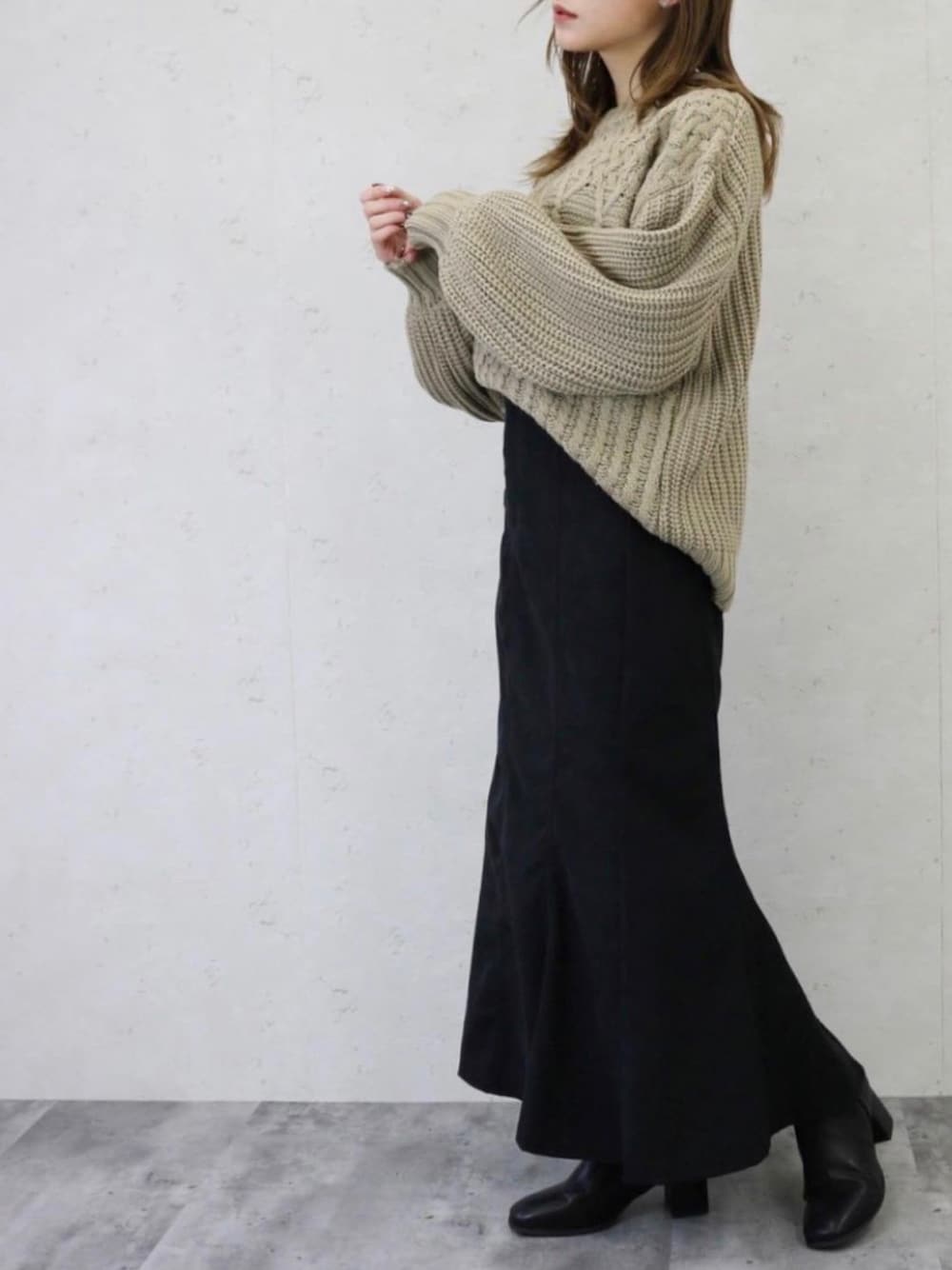 ブラック系のスカート、ベージュ系のニット/セーターを着用したレディースの冬コーディネートの1枚目の写真
