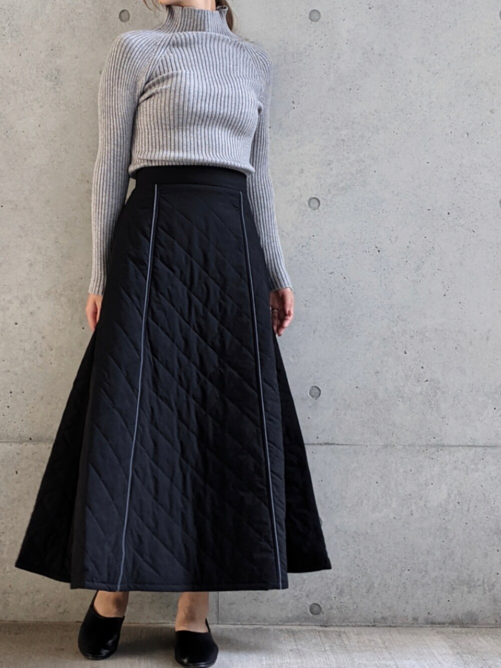 グレー系のニット/セーター、ブラック系のスカートを着用したレディースの秋コーディネートの1枚目の写真