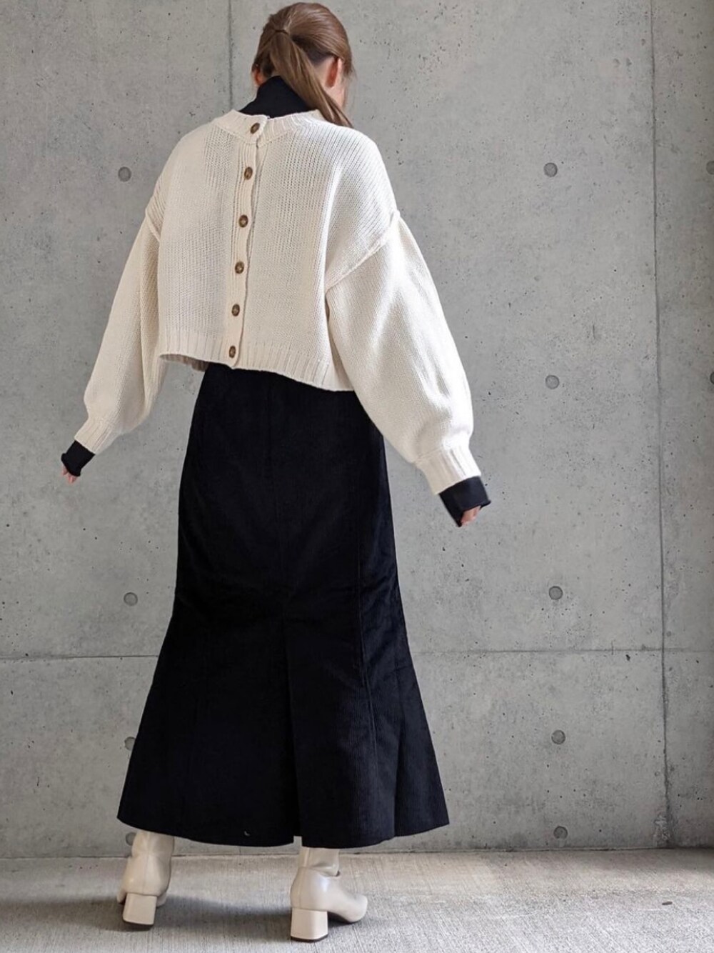 ホワイト系のカーディガン/ボレロ、ブラック系のスカートを着用したレディースの秋コーディネートの1枚目の写真