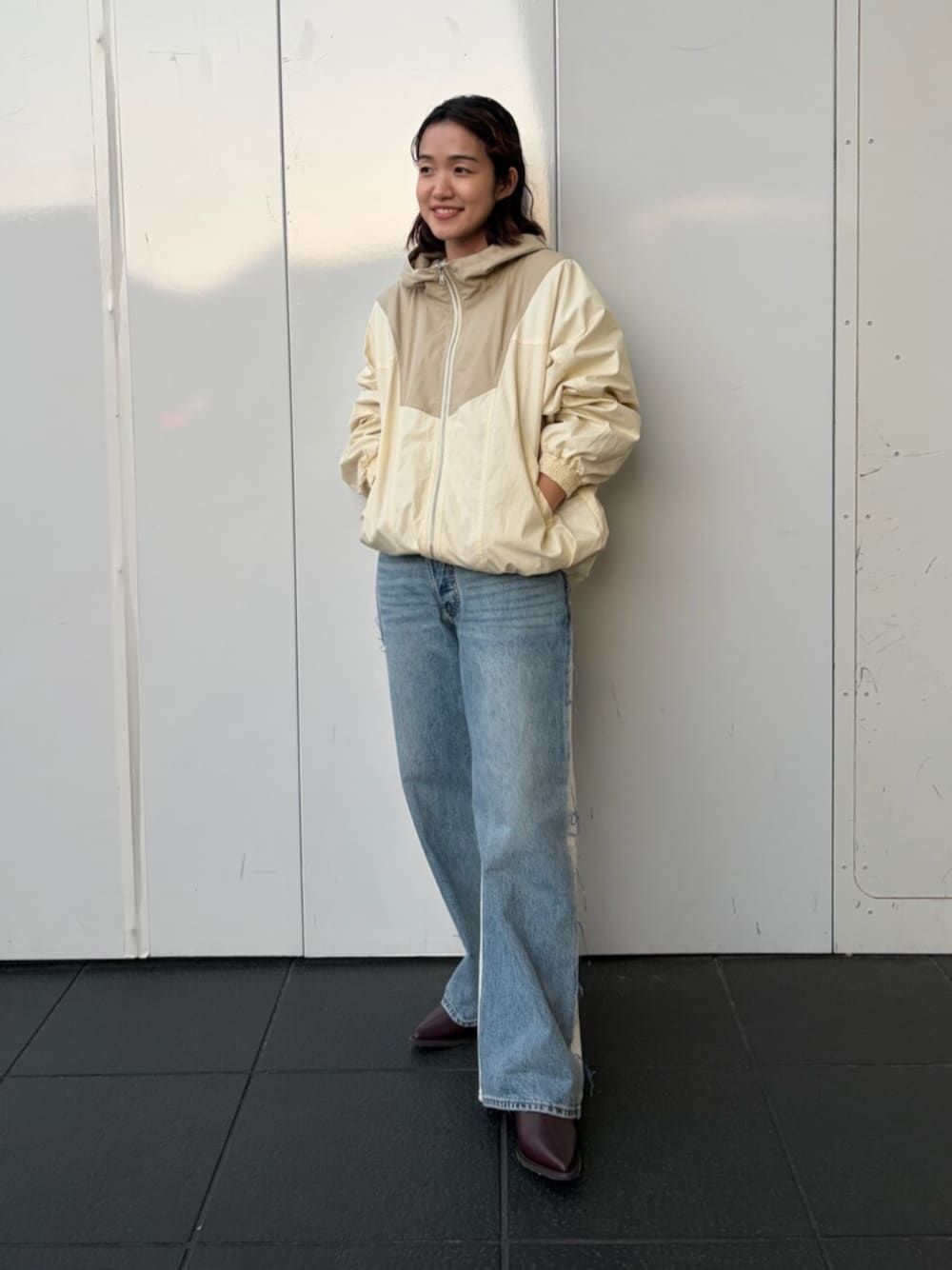 ホワイト系のブルゾン、ブルー系のデニムパンツ、ブラウン系のブーツを着用したレディースの秋コーディネートの1枚目の写真