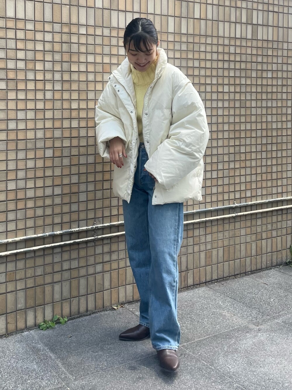 ホワイト系のダウンジャケット/コート、イエロー系のニット/セーター、ブルー系のデニムパンツを着用したレディースの秋コーディネートの1枚目の写真