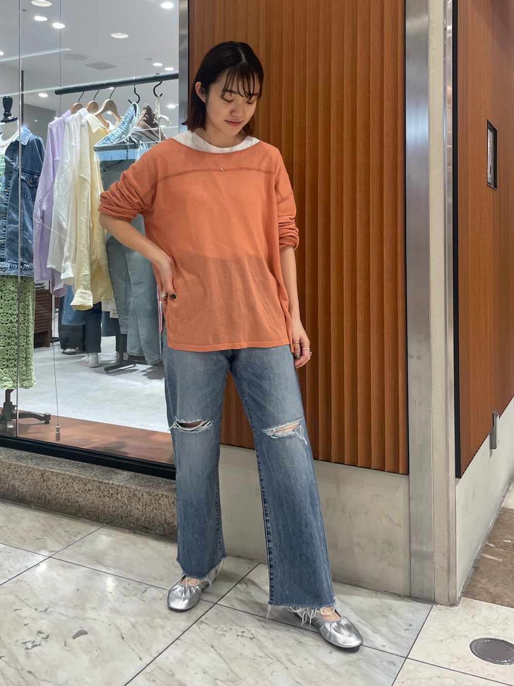 オレンジ系のニット/セーター、ブルー系のデニムパンツ、シルバー系のバレエシューズを着用したレディースの春コーディネートの1枚目の写真