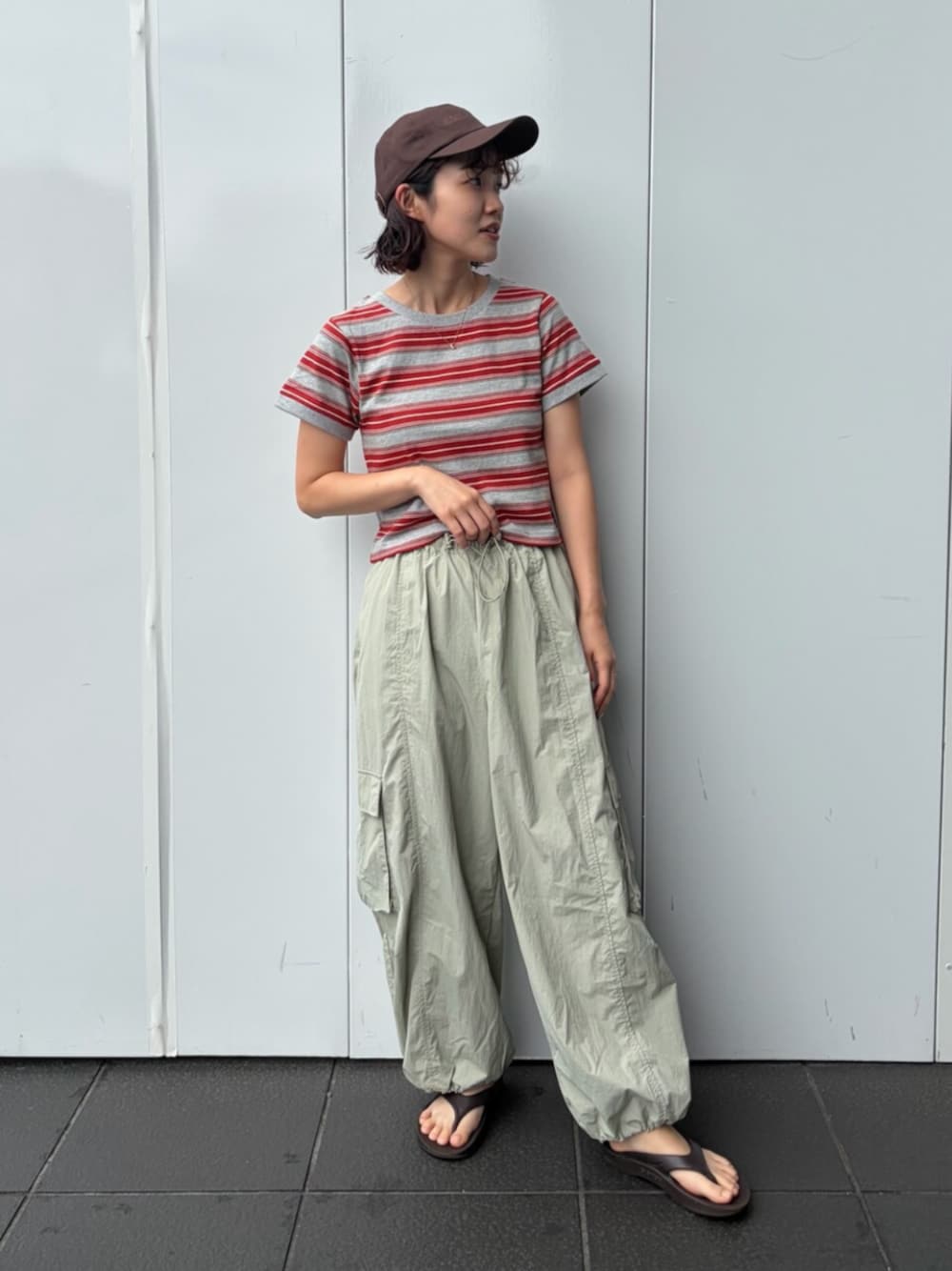 レッド系のTシャツ/カットソー、グリーン系のその他パンツ、ブラウン系のキャップを着用したレディースの夏コーディネートの1枚目の写真