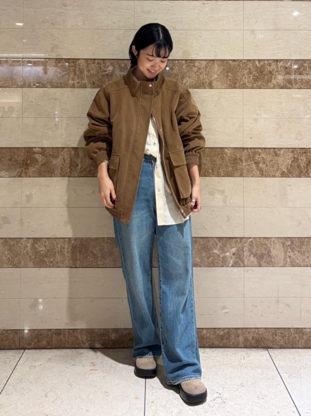 ベージュ系のシャツ/ブラウス、ブラウン系のブルゾン、ブルー系のデニムパンツを着用したレディースの秋コーディネートの1枚目の写真
