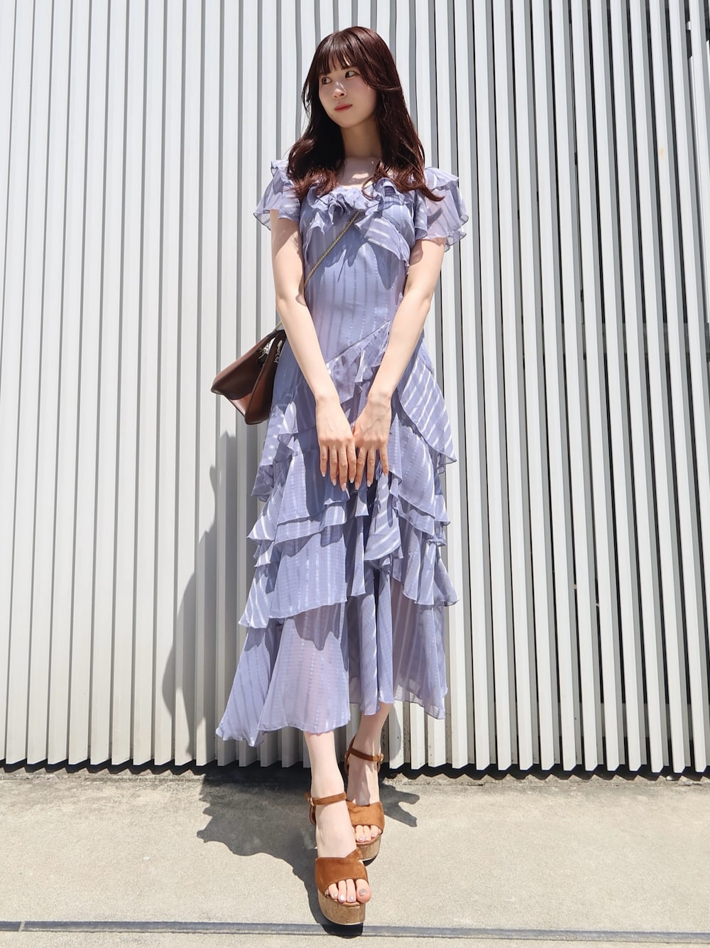 ブラウン系のサンダル、ブラウン系のハンドバッグ、ブルー系のワンピースを着用したレディースの夏コーディネートの1枚目の写真