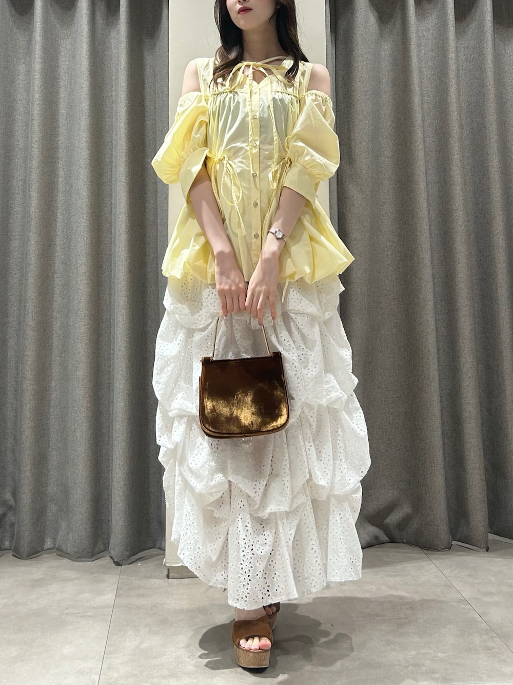 イエロー系のシャツ/ブラウス、ホワイト系のスカート、ブラウン系のサンダルを着用したレディースの夏コーディネートの1枚目の写真