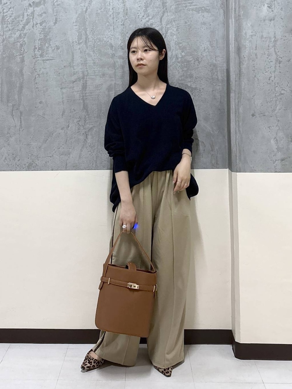 ベージュ系のその他パンツ、イエロー系のハンドバッグ、ブルー系のニット/セーターを着用したレディースの秋コーディネートの1枚目の写真