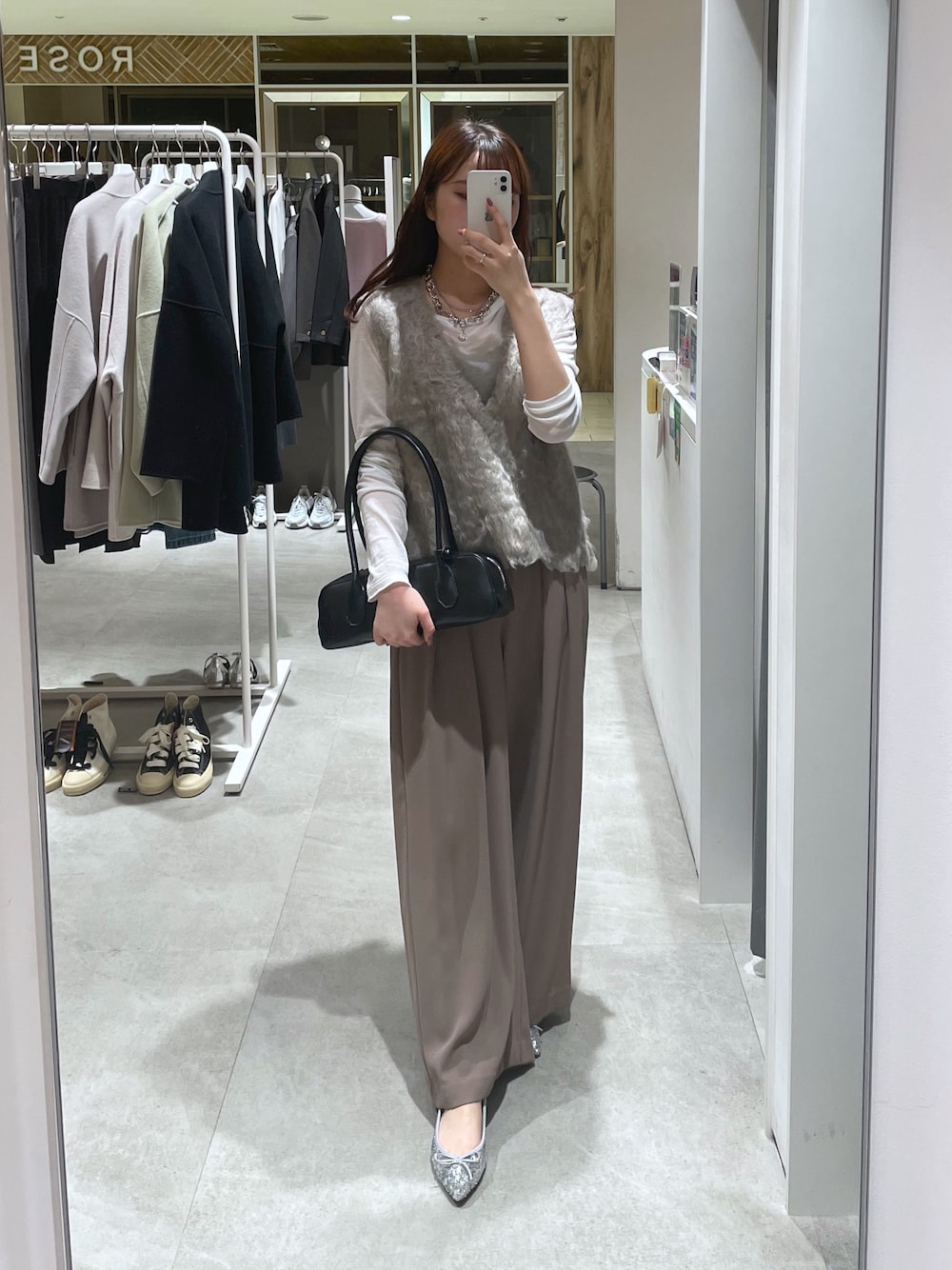 ブラウン系のスラックス、ベージュ系のニット/セーター、ホワイト系のTシャツ/カットソーを着用したレディースの秋コーディネートの1枚目の写真