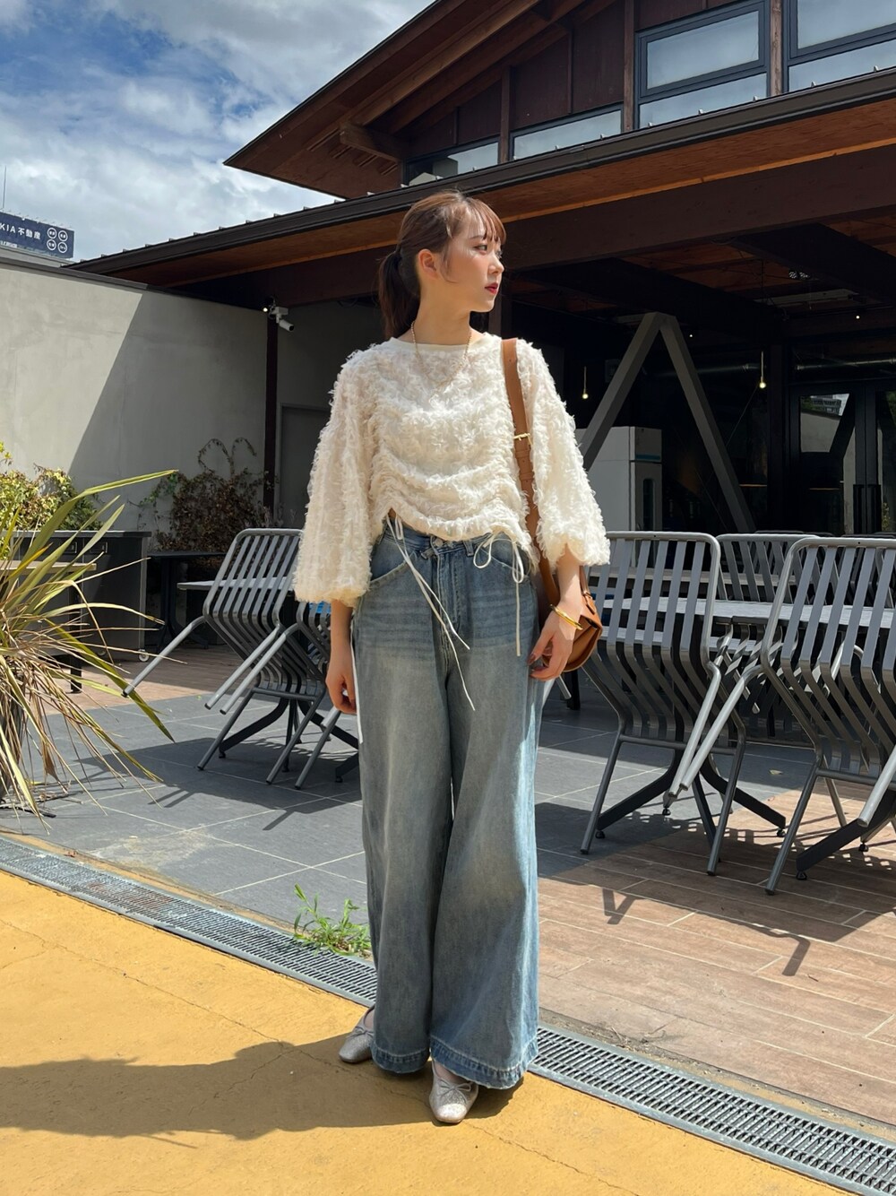 ブルー系のデニムパンツ、ピンク系のバレエシューズ、ブラウン系のショルダーバッグを着用したレディースの秋コーディネートの1枚目の写真