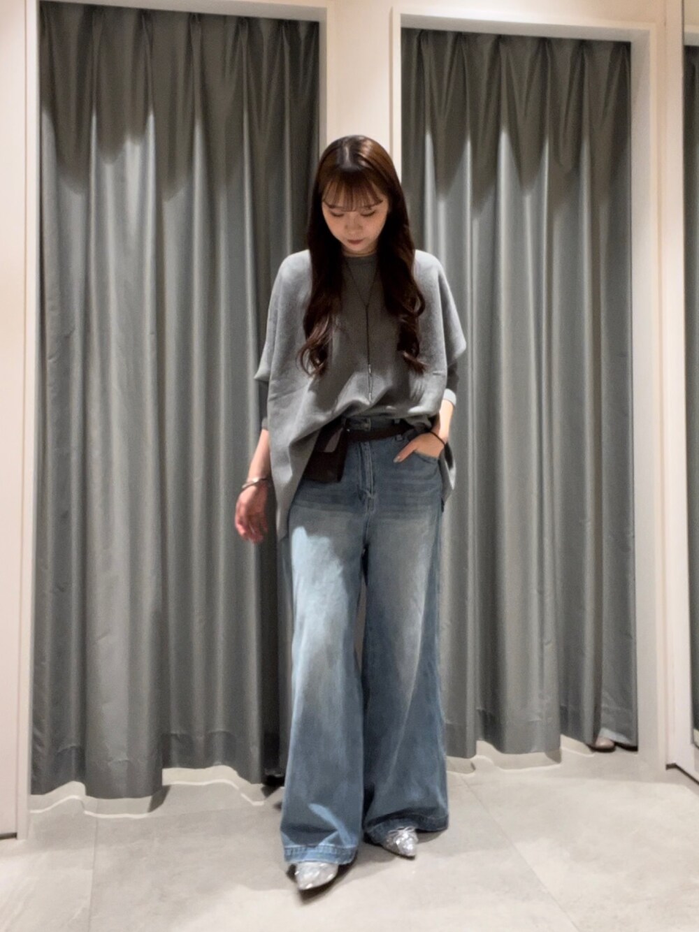 ブルー系のデニムパンツ、シルバー系のパンプス、ブラウン系のショルダーバッグを着用したレディースの秋コーディネートの1枚目の写真