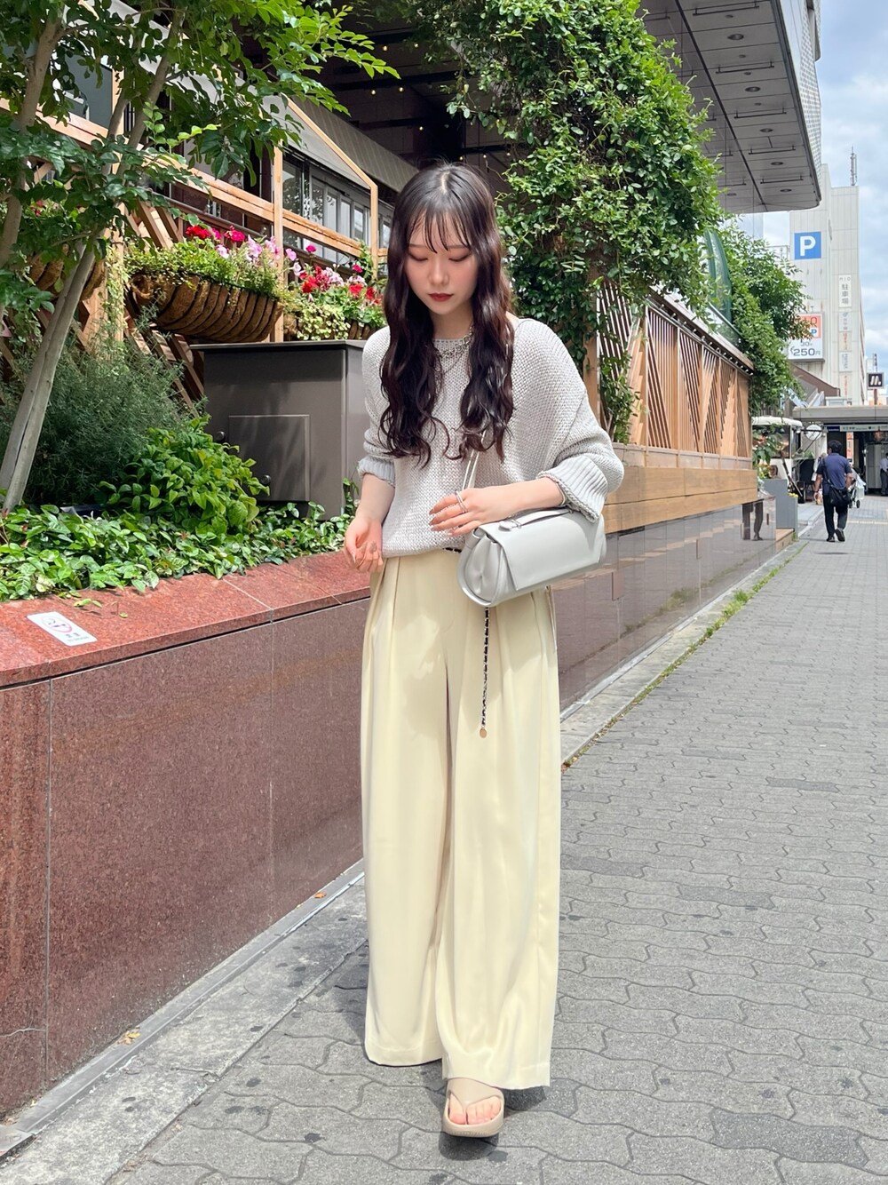 グレー系のニット/セーター、イエロー系のスラックス、グレー系のショルダーバッグを着用したレディースの夏コーディネートの1枚目の写真