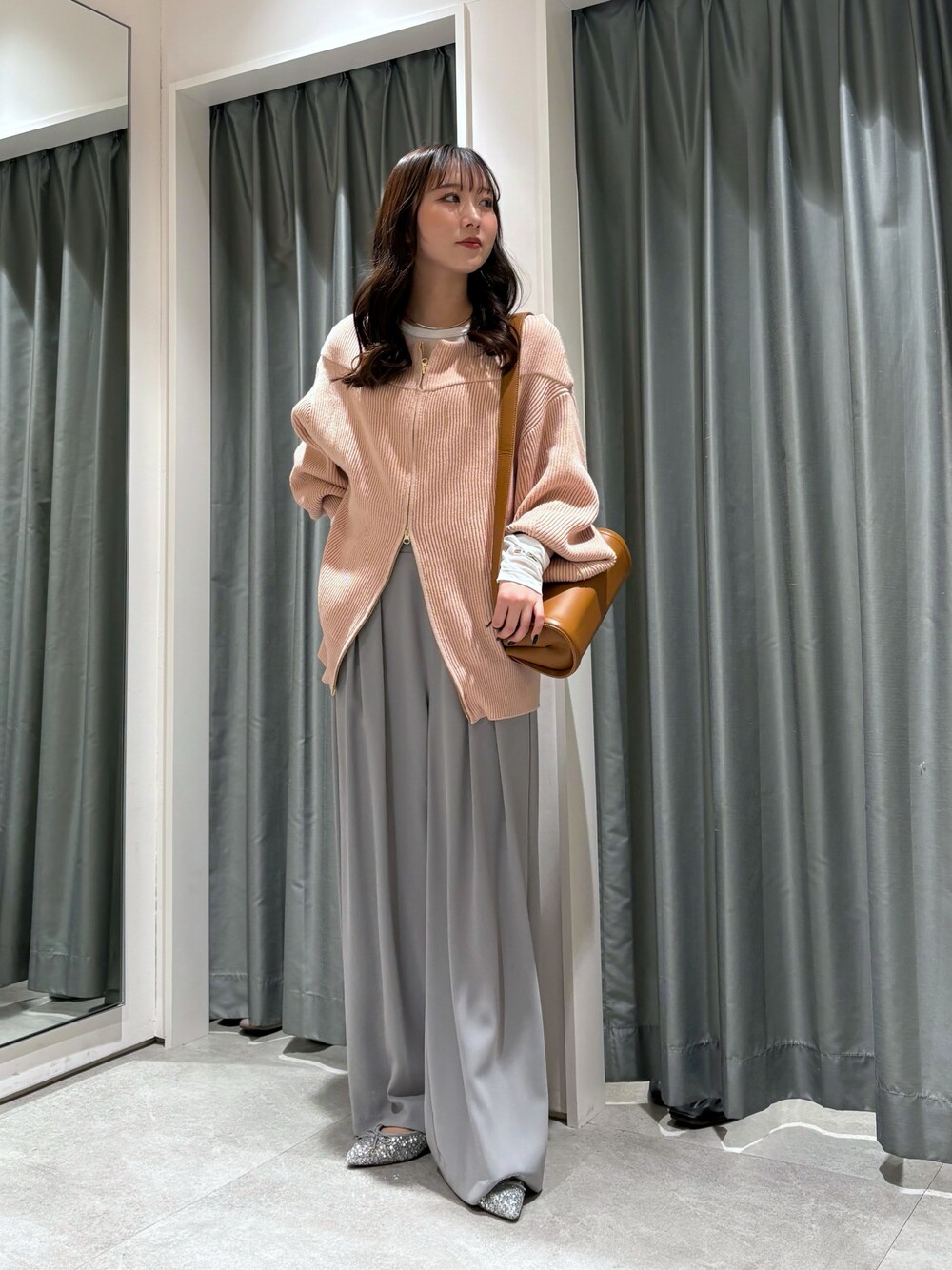 ベージュ系のスラックス、ピンク系のニット/セーター、ブラウン系のショルダーバッグを着用したレディースの冬コーディネートの1枚目の写真