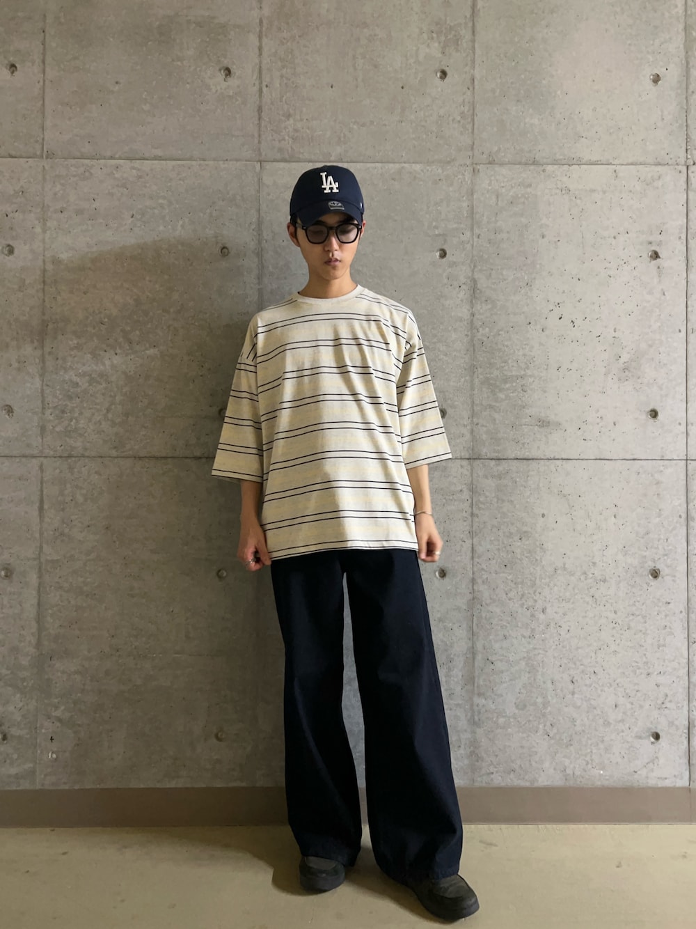 グレー系のTシャツ/カットソー、ブルー系のデニムパンツ、ブラック系のサングラスを着用したメンズの夏コーディネートの1枚目の写真