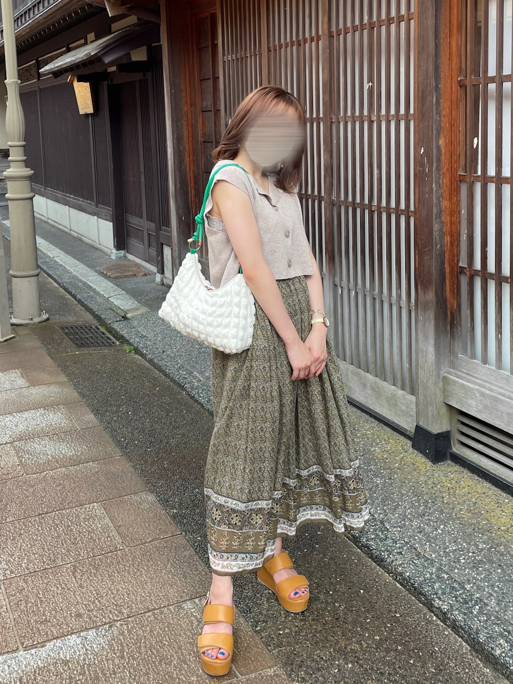グリーン系のスカート、ベージュ系のニット/セーター、ブラウン系のサンダルを着用したレディースの夏コーディネートの1枚目の写真
